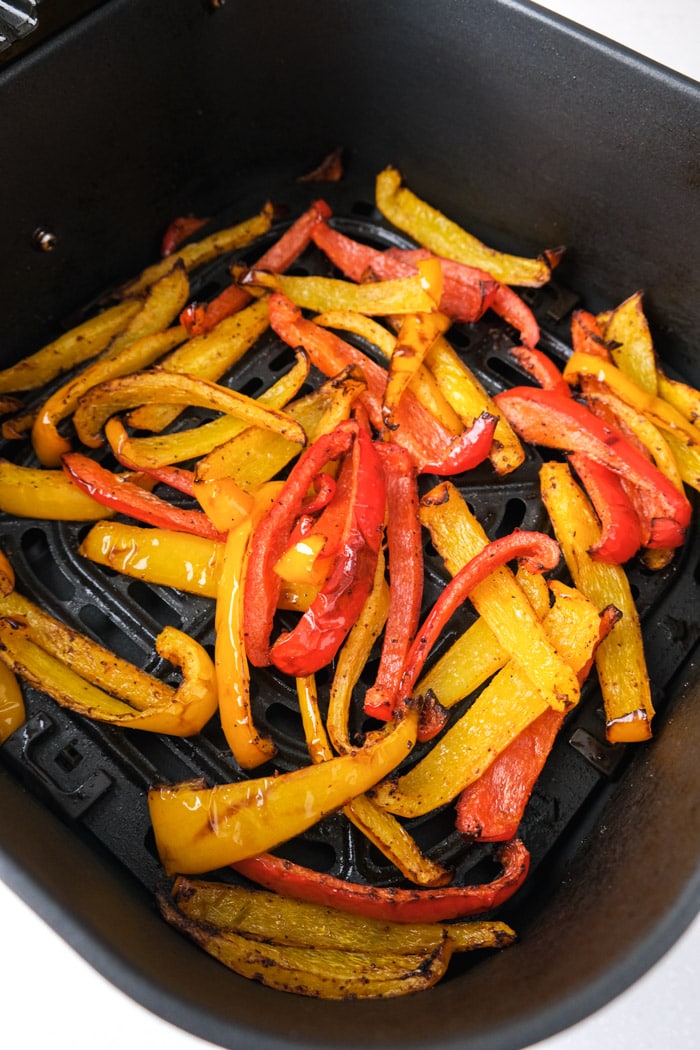 air fryer roasted bell pepper strips in black air fryer basket on counter.
