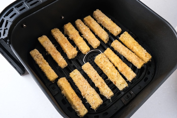 breaded eggplant fries sitting in black air fryer tray on counter.