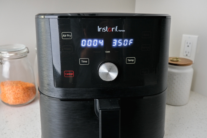 black air fryer with two display screens on panel sitting on counter top.