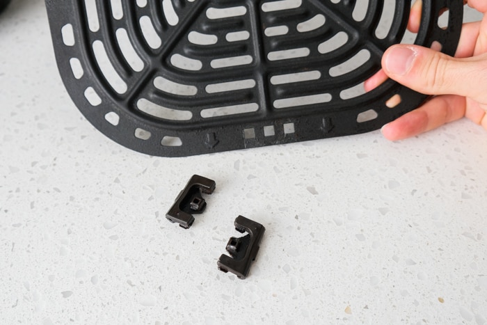 two silicone feet removed from metallic air fryer tray beside on counter.