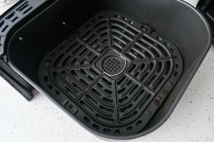 air fryer black basket with metal tray inside resting on counter.