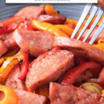 cooked kielbasa and peppers in bowl with fork and text overlay "kielbasa & peppers in the air fryer".