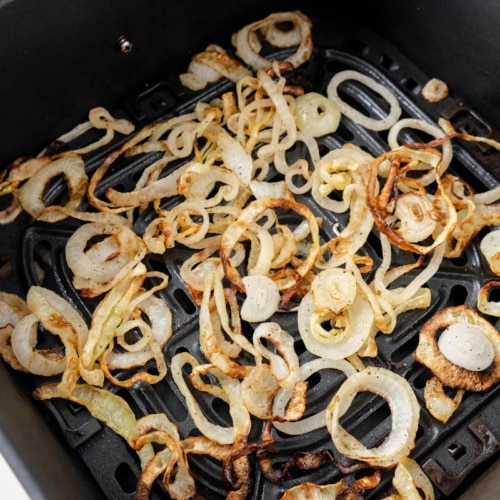 crispy onions sitting in black air fryer tray on counter.