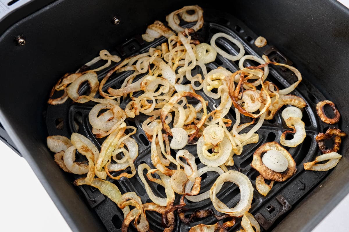 crispy onions sitting in black air fryer tray on counter.