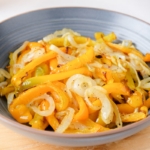 air fried onions and yellow peppers in blue bowl on wooden board.
