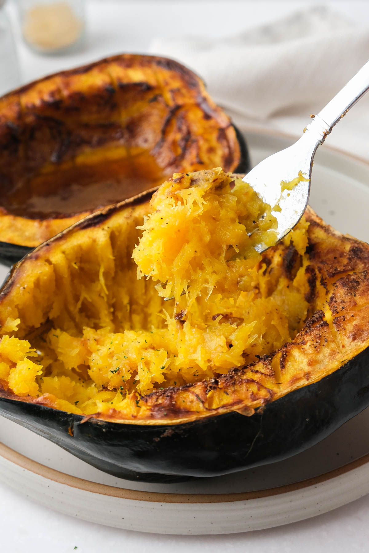 half acorn squash cooked with silver fork pulling squash from inside.