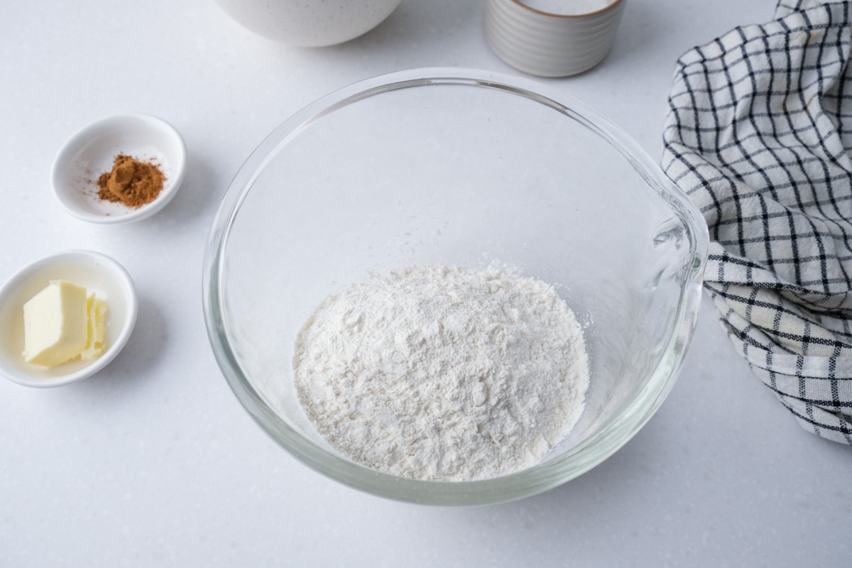 flour in glass bowl on counter top with other ingredients around.