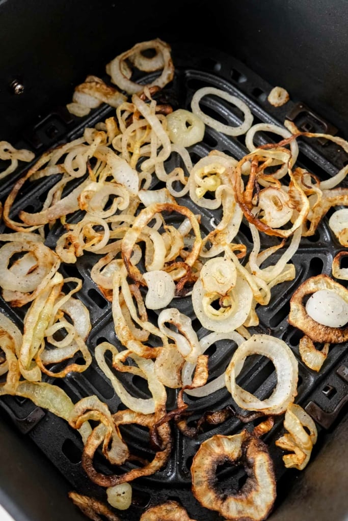 air fried onions sitting in black air fryer basket on counter top.