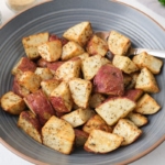 blue bowl with roasted red potatoes and fork sticking out.