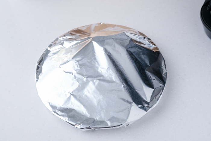 plate covered in ton foil sitting on white counter.