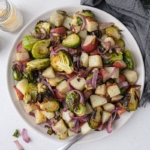 plate heaping with brussels sprouts and potatoes with grey cloth beside on counter.