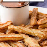 churros coated with cinnamon sugar on plate with mug of hot chocolate and text overlay "crispy churros in the air fryer".