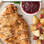 sliced turkey breast on plate with cranberry sauce and potatoes plus text overlay "turkey breast in the air fryer".