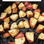 red potato cubes in black air fryer with text overlay "red potatoes in the air fryer".