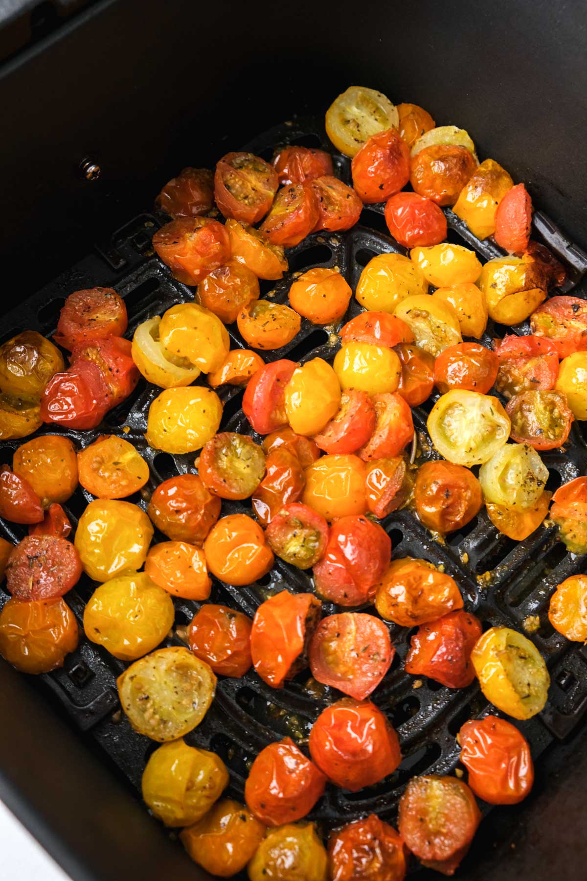 air roasted cherry tomatoes in black air fryer tray on counter.