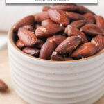 roasted almonds in small bowl with sea salt on top and text overlay "roasted almonds in the air fryer".