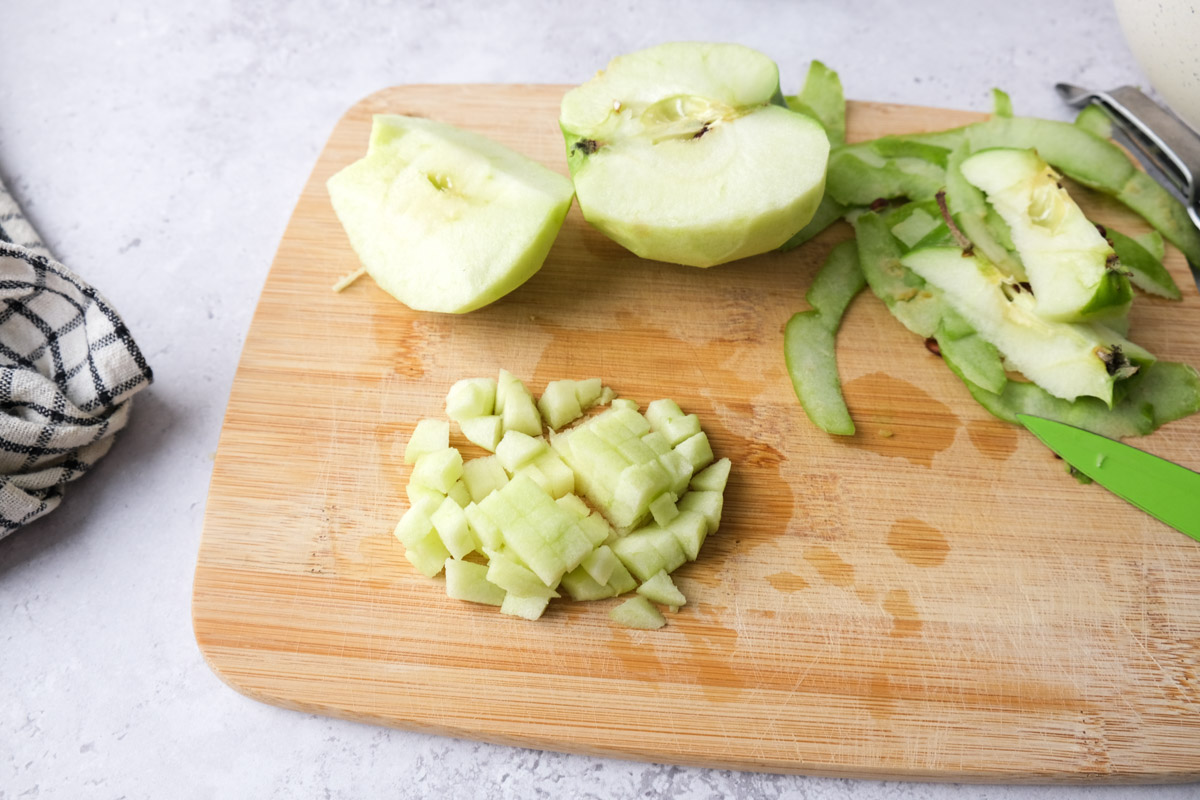 green apple cut into small pieces on wooden cutting board.