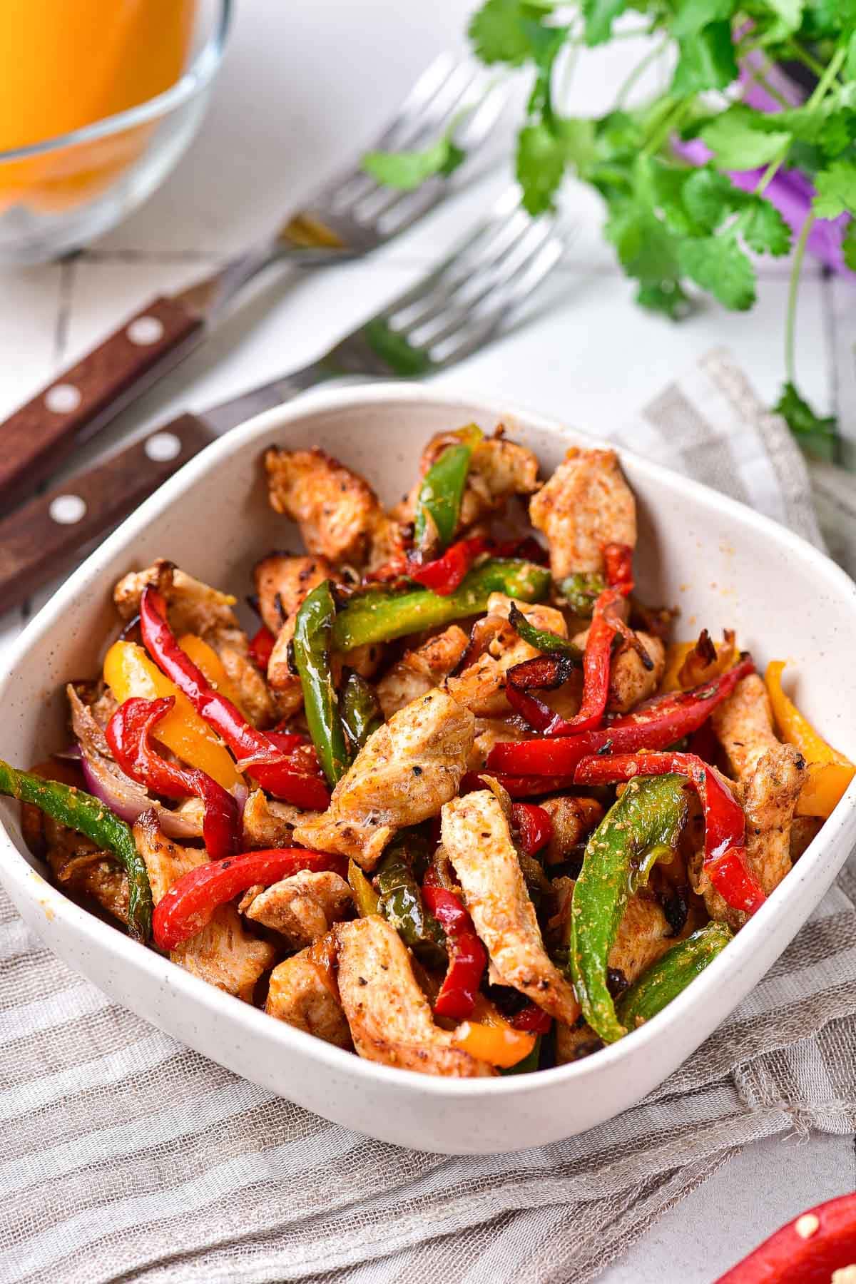 pieces of cooked chicken and peppers in white bowl on counter.