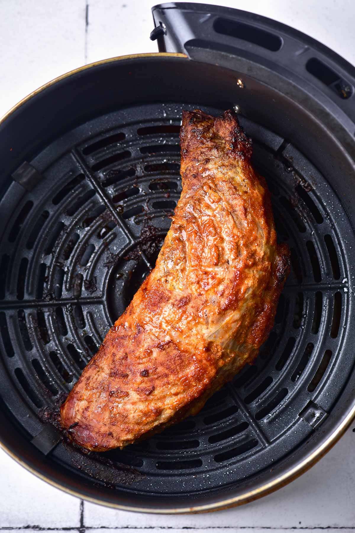 crispy pork tenderloin in black air fryer basket.