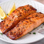 two cooked filets of honey garlic salmon on white plate.