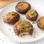 roasted stuffed mushroom caps on white plate with parsley around.