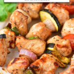 cooked chicken kabobs on white plate with text overlay 