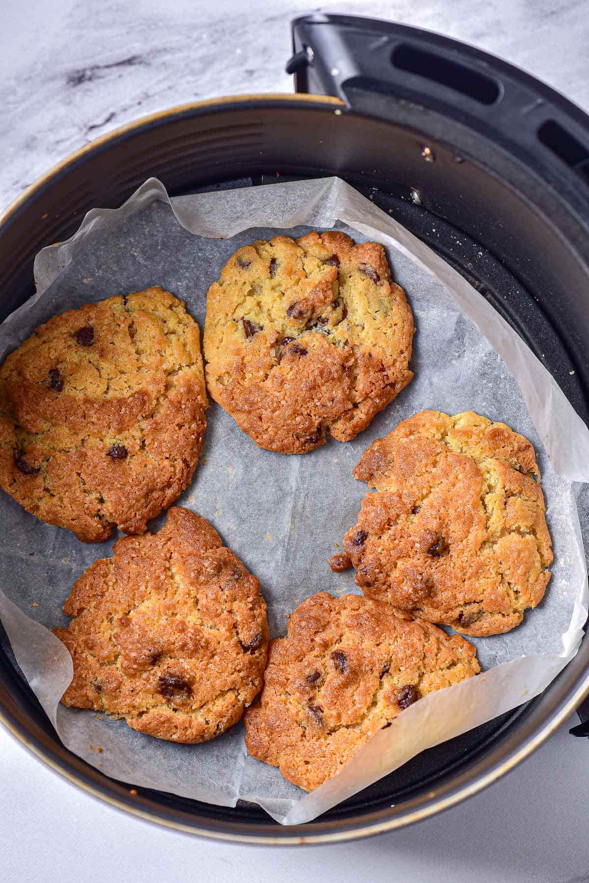 crispy chocolate cookies on parchment paper in round air fryer basket.