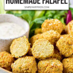 cooked falafel in bowl with vegetables and dipping sauce plus text overlay 
