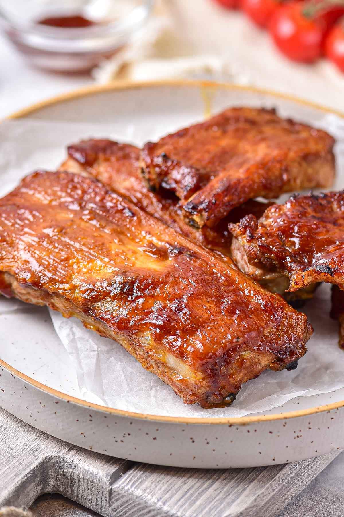 three pieces of cooked ribs on plate sitting on table.