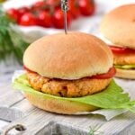 cooked salmon burgers on buns with lettuce and tomato slice.