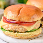 turkey burger on bun with toppings on white marble platter.