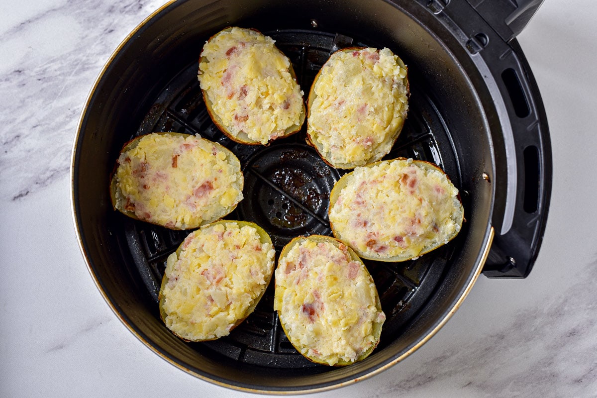 twice baked potato halves arranged in circle in black air fryer basket.