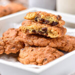 stack of chocolate chip cookies in large white tray on counter.