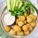 plate of round falafel with white sauce in small bowl beside.
