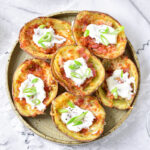 six crispy potato skins on a round plate on counter with cloth underneath.