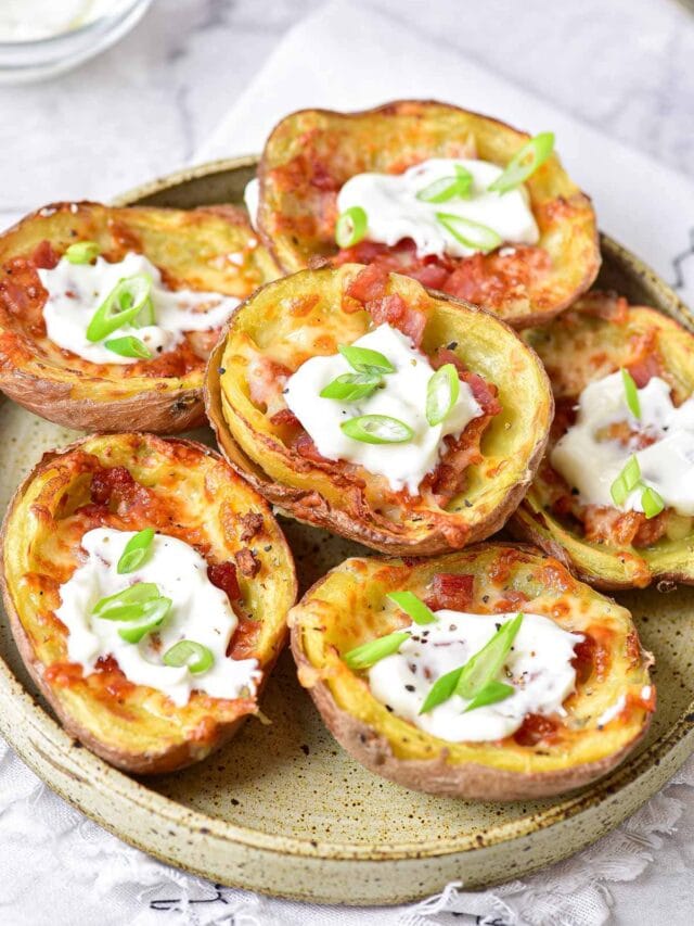 crispy potato skins with sour cream on top on plate with cloth under.