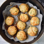 cooked chicken meatballs in round air fryer basket on counter.