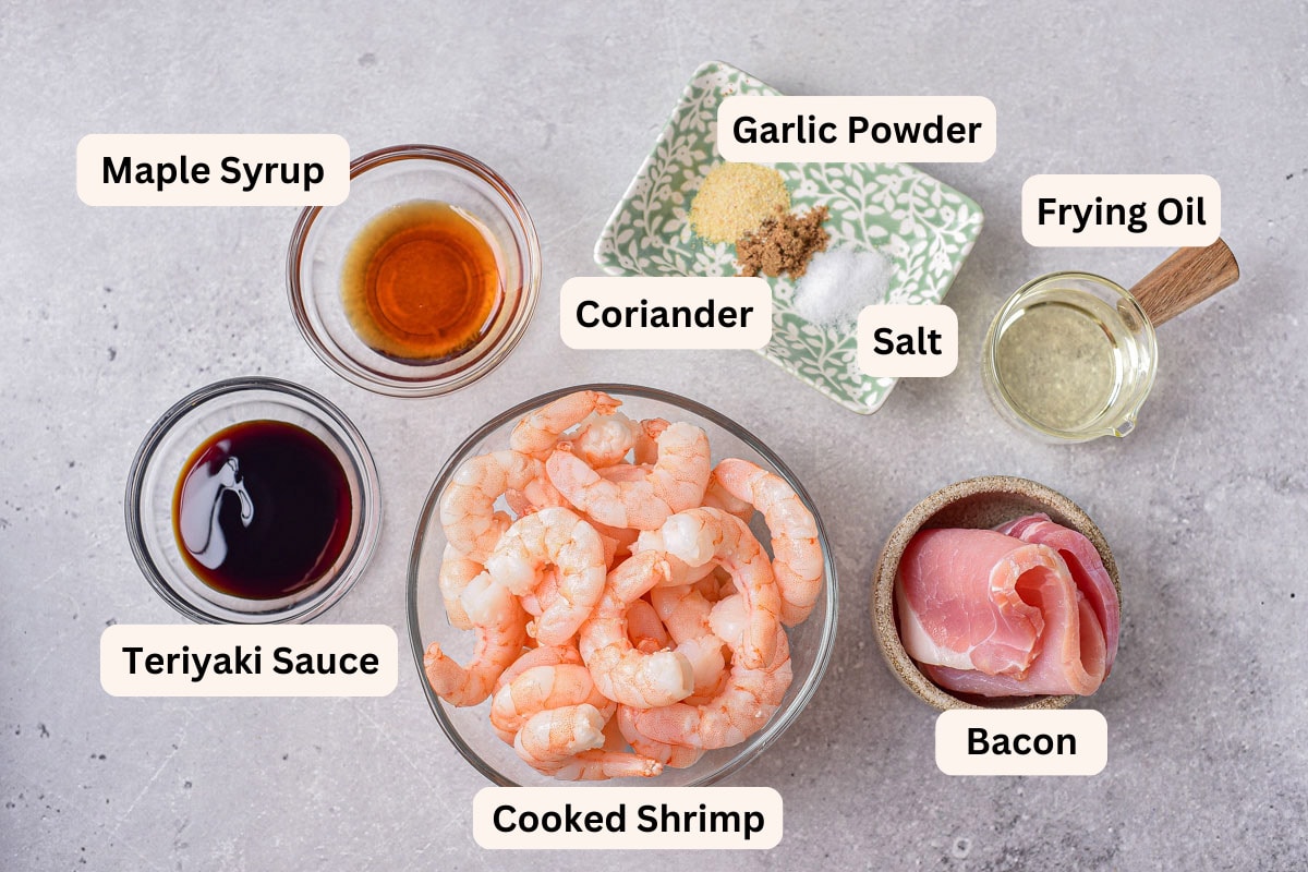 ingredients to make bacon wrapped shrimp on counter in bowls with labels.