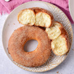 whole donut seen from top down on plate beside two halves of a ripped donut.