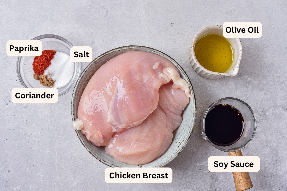 ingredients to make air fryer chicken bites in bowls or plates on counter with labels beside.