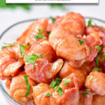 cooked bacon wrapped shrimp in clear bowl with text overlay "bacon shrimpin the air fryer".