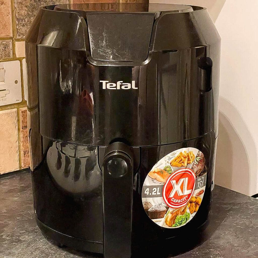 black t-fal air fryer on kitchen counter with tile behind.