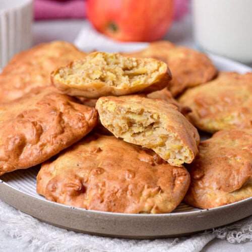 apple fritters stacked on plate with cloth underneath.