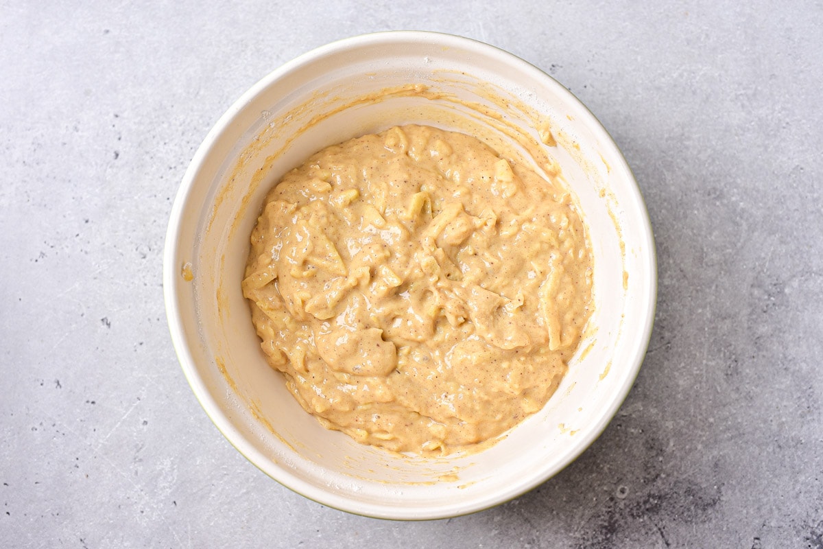 thick batter for apple fritters in mixing bowl on counter.
