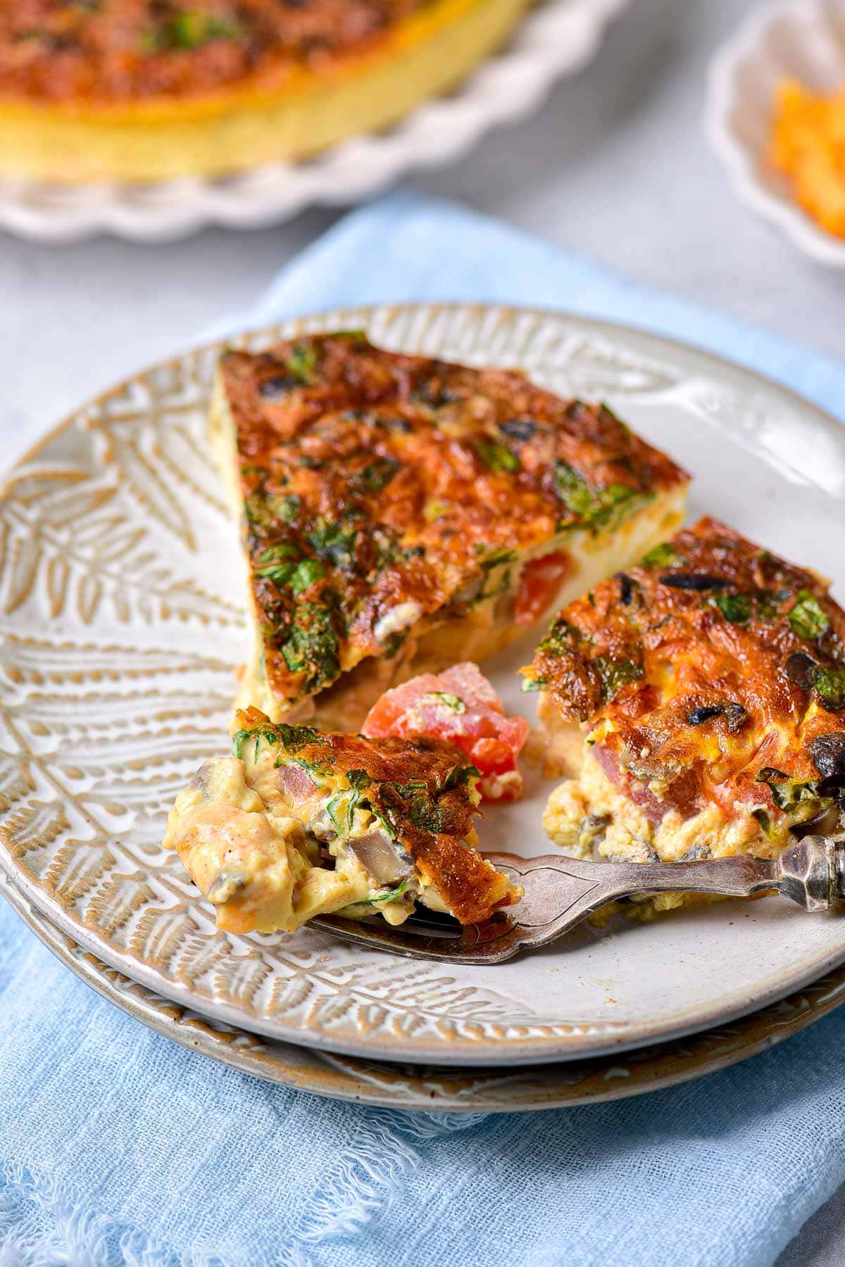 two slices of cooked frittata in plate with fork removing a bite.
