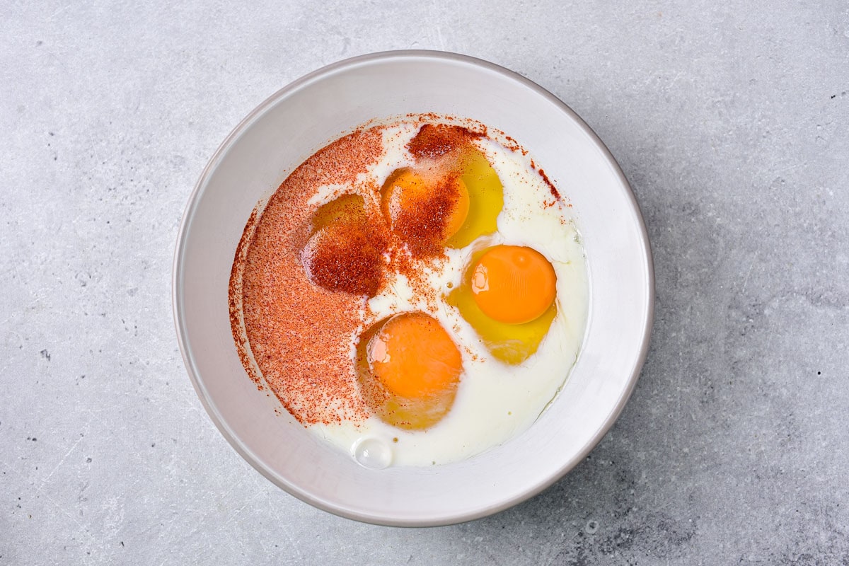 raw eggs and spices in white bowl on counter.