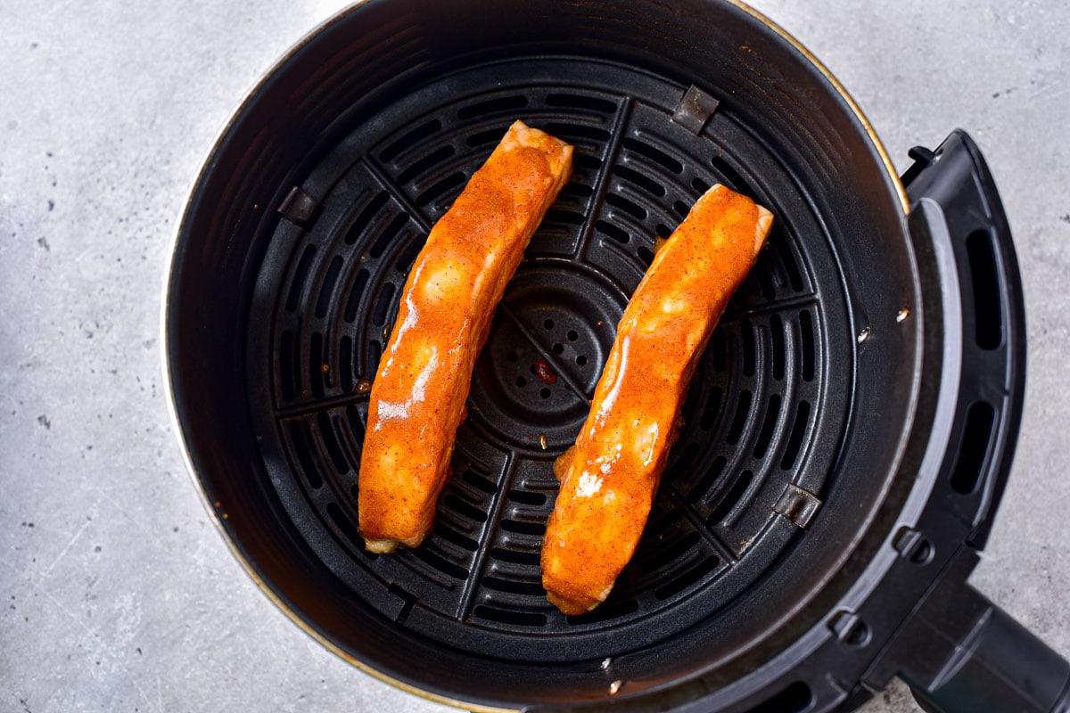 honey mustard salmon fillets in round black air fryer basket.
