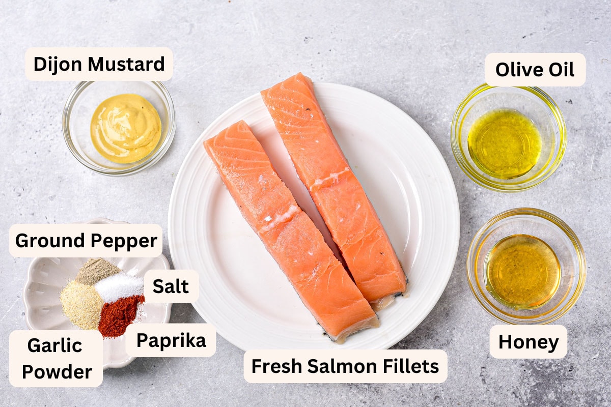 ingredients to make honey mustard salmon in bowls on counter with labels.