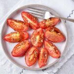 plate with roasted tomato wedges and silver fork beside.