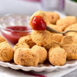 homemade tater tots piled on white plate with ketchup behind.